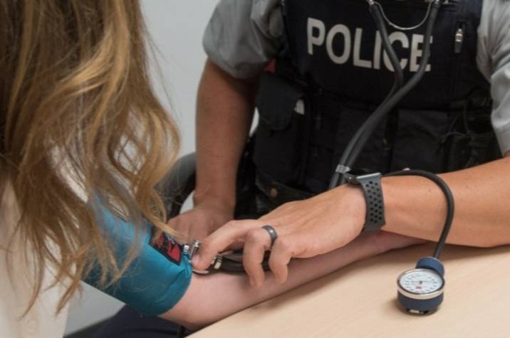 Police officer tests woman's blood pressure.
