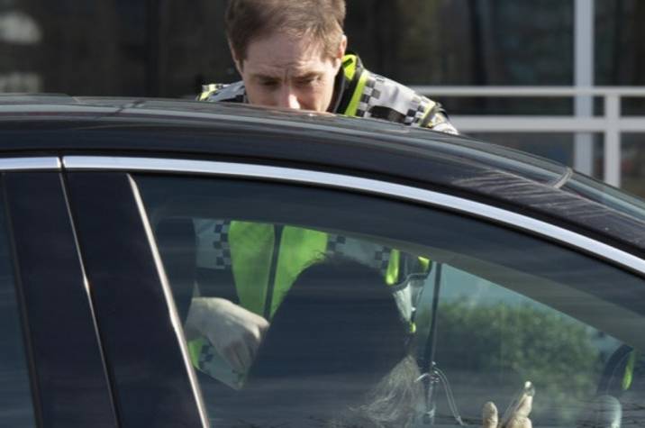 Police officer speaking to the driver of a car.