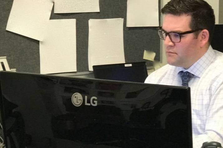 Man sits at desk behind computer.