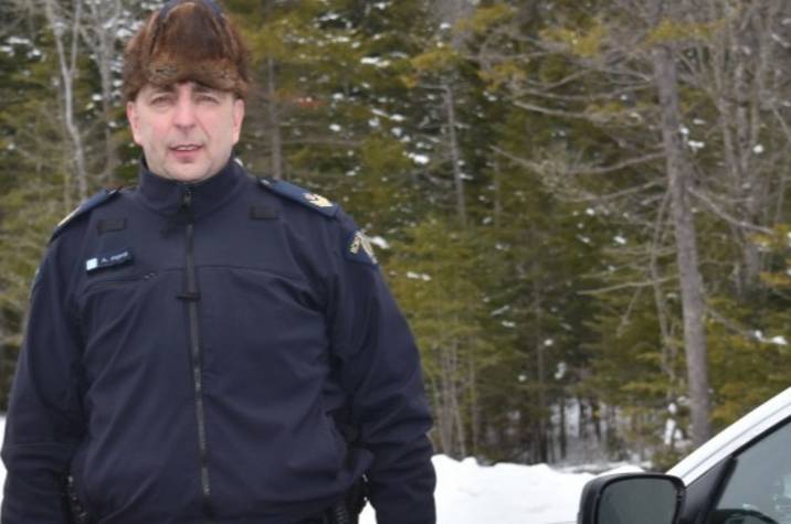 Male police officer stands on road.