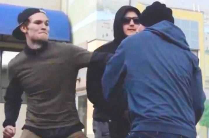 Young people have a fist fight in front of an urban building.