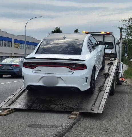 Photo of white Dodge Charger being loaded onto a tow truck
