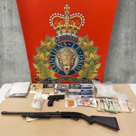 Drugs, guns and cash displayed on a table with the RCMP logo in the background