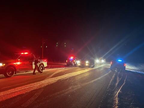 A check stop with stopped police and civilian vehicles on a road at night