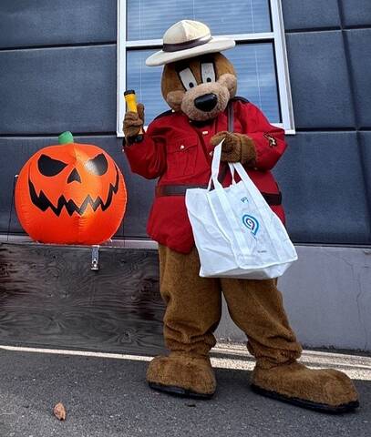 Image of Sgt. Safety Bear beside a pumpkin holding a flashlight and a white bag.