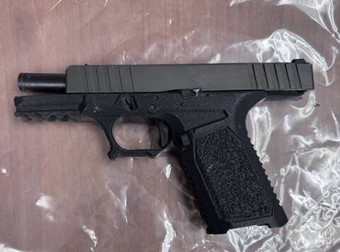 A black 3D printed handgun lying flat on a table.