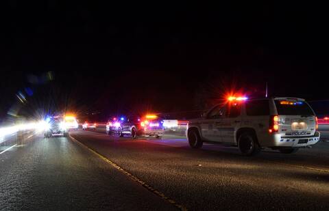 BC Highway Patrol cruisers with their emergency lights activated as they block a highway in the darkness