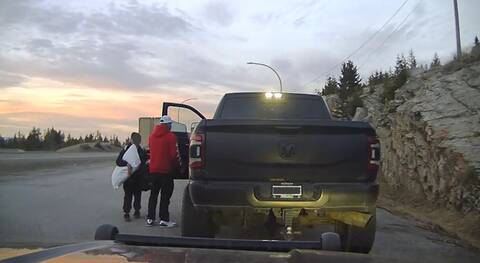 A man and his son take belongings out of a Dodge pickup that is being towed to an impound lot