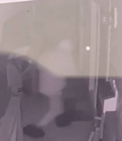 A surveillance photo of a suspect breaking into a building.