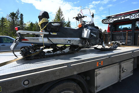The recovered stolen black and silver ski-doo snowmobile strapped to flat deck tow truck.