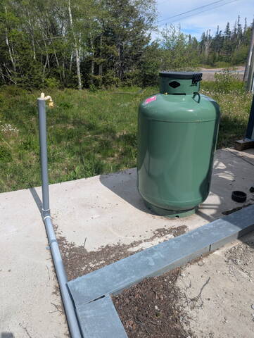 A photo of a single large propane tank at a communications tower.