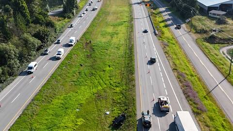 An aerial view of Highway #1 near Cole Road in the hours after the collision that shows a rolled over green Subaru Impreza and police vehicles