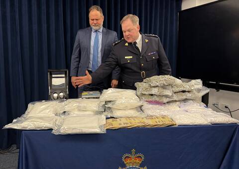 Supt. Jeff Asmundson (right) and Manitoba Justice Minister Matt Wiebe survey more than $1.5 million in drugs and cash seized as part of Project Deepwater on March 9, 2026.