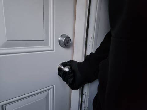 Person dressed in all black opening a door.