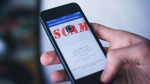 Picture of cell phone in a hand with “scam” on the screen