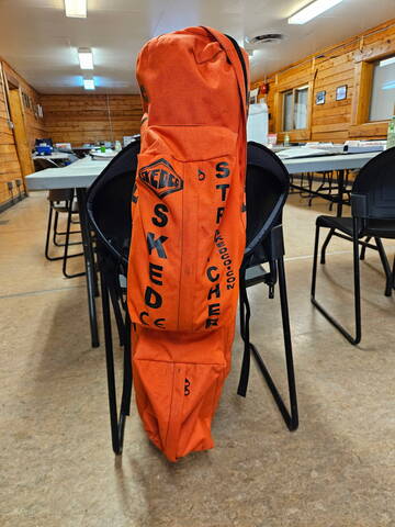 An orange rescue stretcher marked “SKED STRETCHER”