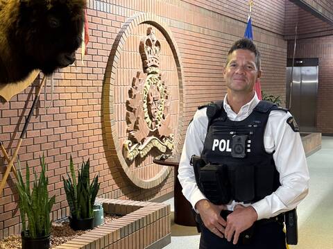 Inspector Lee Nelsen standing next to a wall with an RCMP logo