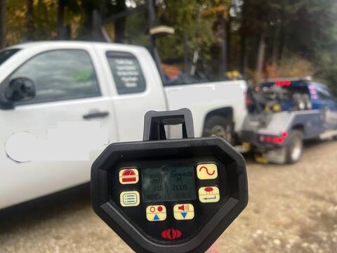 A white Chevrolet Silverado traffic control truck is towed away while a BC Highway Patrol laser reader shows a readout of 110 km/h