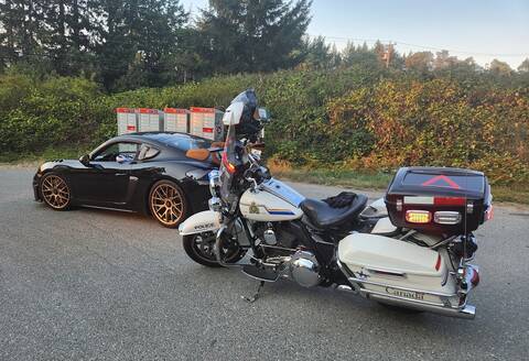 A police motorcycle behind a black Porsche that was impounded for excessive speeding on the Island Highway