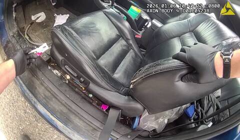 A police officer holds drug paraphernalia while searching the vehicle of a man who was arrested for driving while smoking crack cocaine