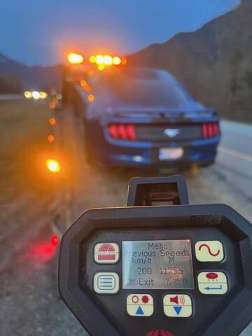 A blue Ford Mustang being loaded onto a tow truck as a laser reader shows a speed of 200 km/h