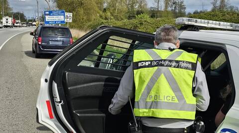 A BC Highway Patrol officer stops a blue minivan with a forged Temporary Operating Permit on Highway #99