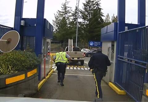 Two BC Highway Patrol officers run to stop a brown, Dodge Ram pickup truck at Horseshoe Bay Ferry Terminal