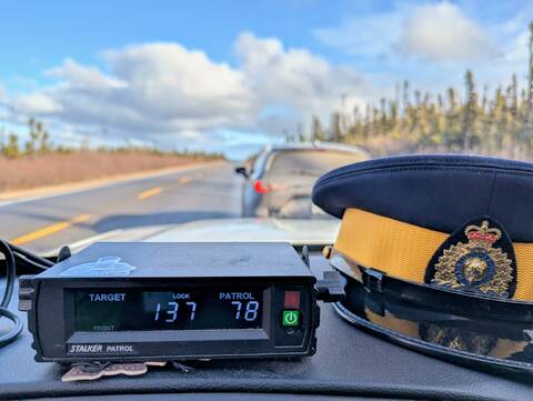 A vehicle is pulled over on the side of a road. A police vehicle’s radar is pictured in the foreground displaying a speed of 137 km/hr. A RCMP cap is also visible in the image. / Un véhicule est arrêté sur le bord d'une route. Le radar d'un véhicule de police est illustré au premier plan, affichant une vitesse de 137 km/h. Une casquette de la GRC est également visible sur l'image.