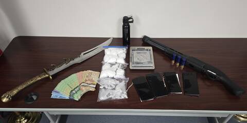 Weapons, cash and small bags of drugs displayed on a table. | Armes, argent liquide et petits sachets de drogue exposés sur une table.