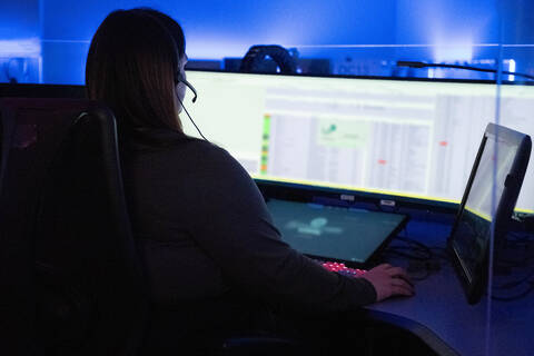 Woman at desk in front of a computer wearing a headset.