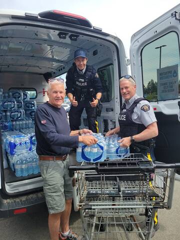 R/Cst Gary O'Brien, Brian Cornborough, President of the local Crime Stoppers, handing water off to Cst Daryl Chow