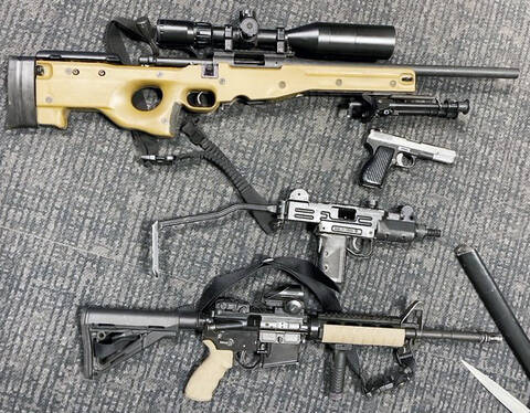 Four guns placed on the floor next to each other including, a loaded prohibited pistol, carbine rifle, a rifle and replica submachine gun.//Quatre armes placées sur le sol les unes à côté des autres, dont un pistolet prohibé chargé, une carabine, un fusil et une réplique de pistolet-mitrailleur.