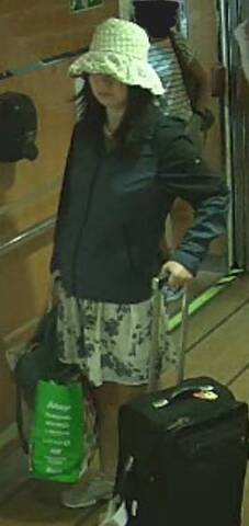 A surveillance image of Ping Chang. She is wearing a light coloured floral skirt, dark jacket, running shoes and a light coloured hat. She is carrying a large reusable shopping bag and purse, and has a black suitcase./Image de Ping Chang provenant de la vidéosurveillance. Elle porte une jupe à fleurs de couleur claire, une veste foncée, des chaussures de sport et un chapeau de couleur claire. Elle porte un grand sac à provisions réutilisable et un sac à main, ainsi qu’une valise noire.