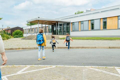 Stock photo of children walking in front of a school.