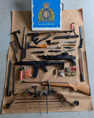 Photo of prohibited weapons, fake firearms, real ammunition, and drugs with a poster displaying the blue RCMP emblem from the Sea to Sky corridor