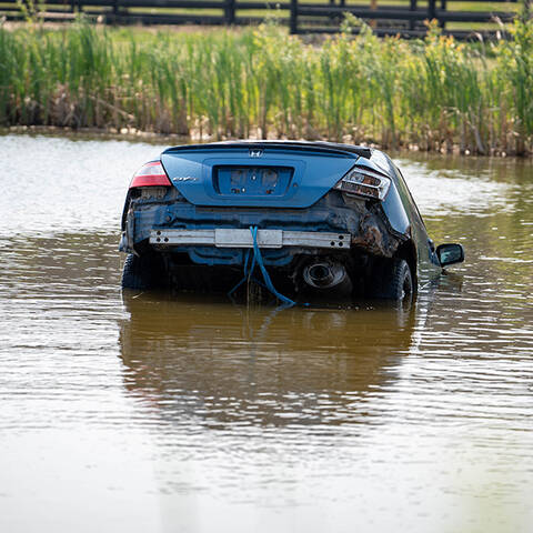 A blue car, that is partially submerged in a pond is pictured. The photo was taken during an RCMP Underwater Recovery Team (URT) training exercise.