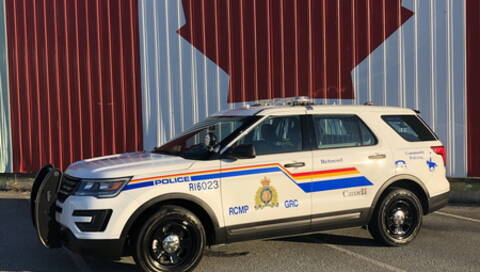 Un véhicule de police garé devant un drapeau canadien.