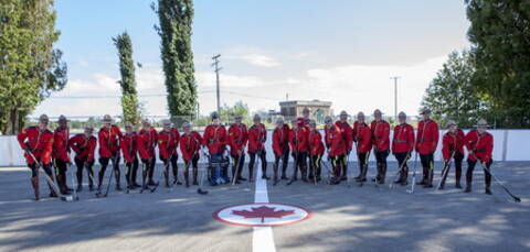 Des membres de la GRC portant la tunique rouge et tenant des bâtons de hockey.
