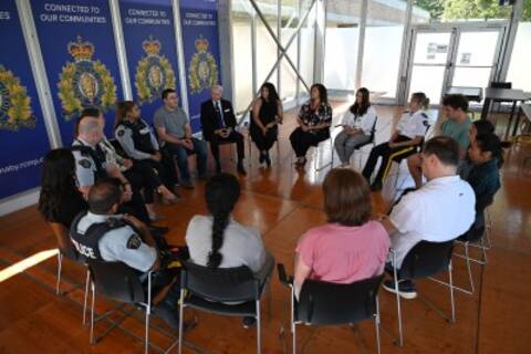 Un groupe de personnes assises en cercle à l'intérieur d'un bâtiment portant les logos de la GRC