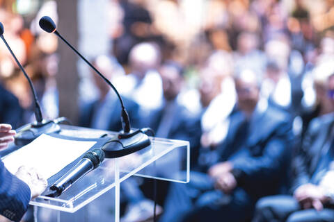 Image de photothèque d’un conférencier sur un podium s’adressant à un auditoire lors d’une conférence de presse.
