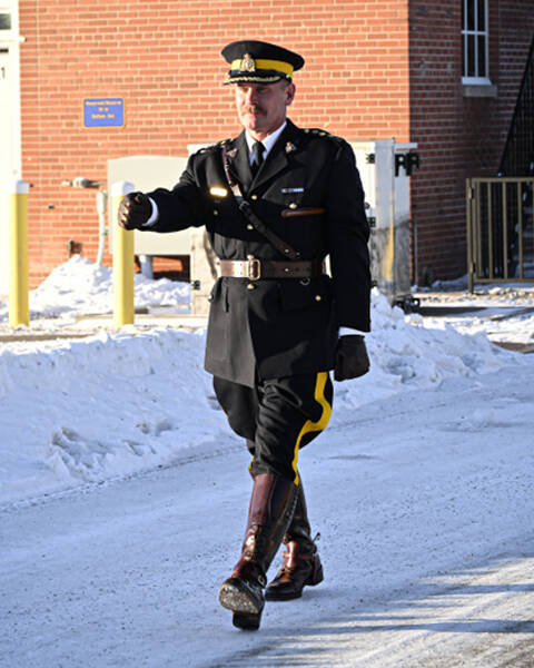 Chief Superintendent Mike Lokken walks down a street in front of a red brick building.